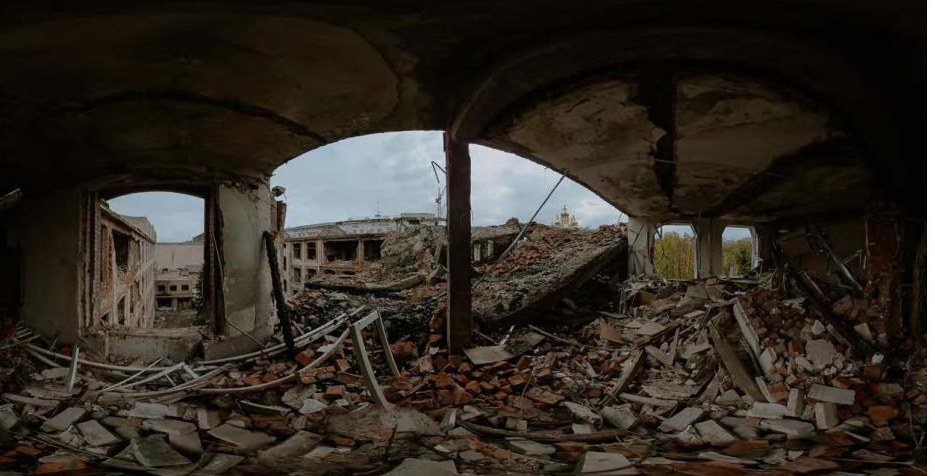 A wide view from inside a ruined building: collapsed floors, rubble, sky through the arches.